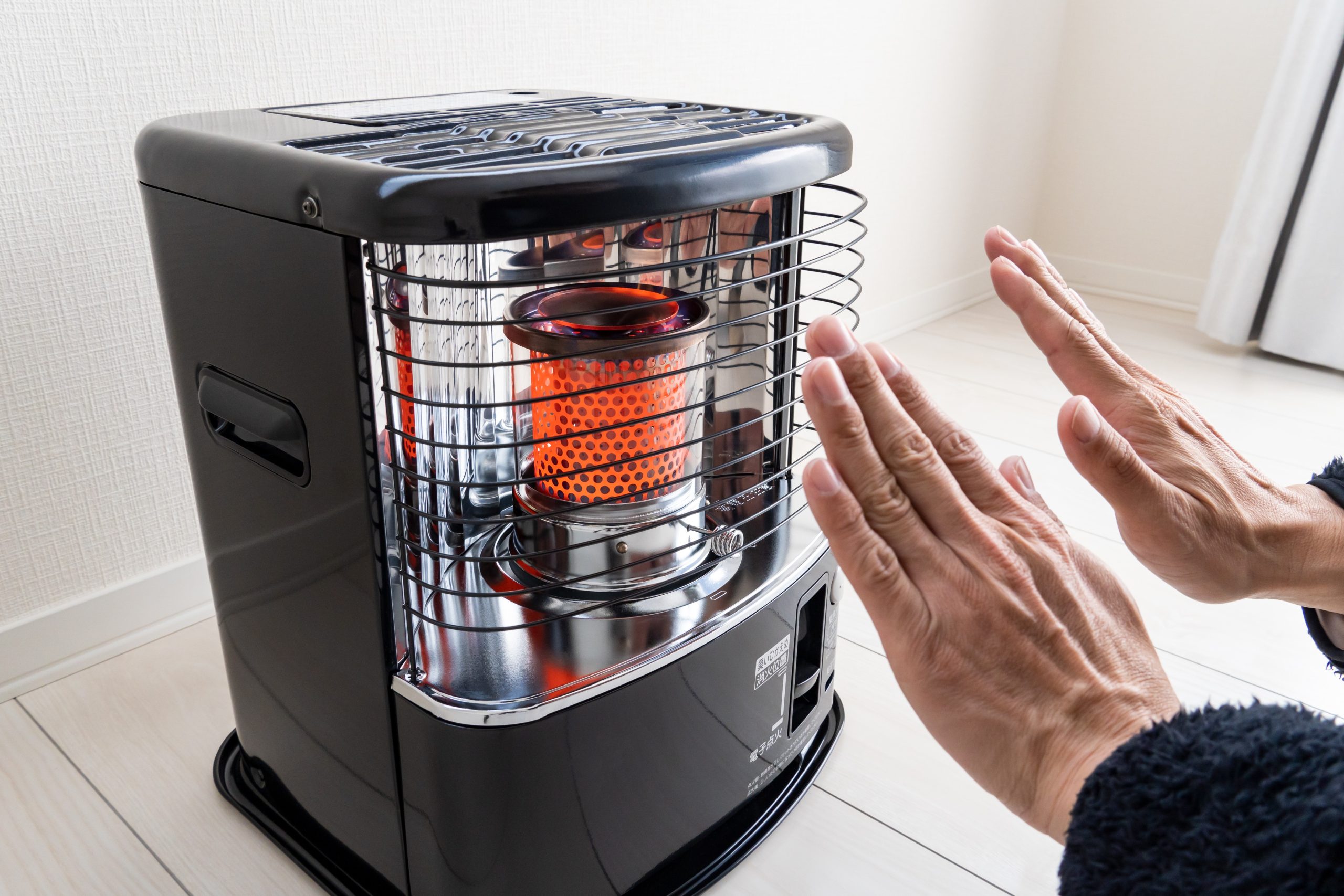 Hands warming in front of a portable indoor heater, illustrating heater safety tips for a warm and comfortable space.